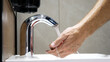 A man washes his hands using a touchless faucet close-up