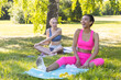 © ArtSys - Two diverse young beautiful girls practicing fitness or yoga outdoors in the park. Concept of females doing sport together. African American, Caucasian models. Healthy active lifestyle, wellness