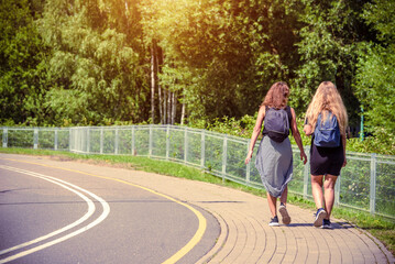 Wall Mural - Two girlfriends walk along a path in the Park
