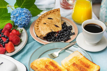 Cute breakfast with fruits and coffee in the garden, blue hydrangea flowers.
