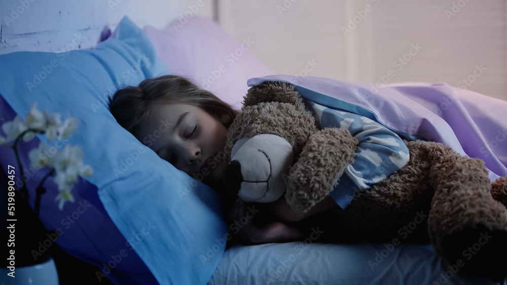 Preteen kid hugging soft toy while sleeping on bed at home. Stock Photo ...
