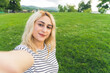 © PoppyPix - blond cheerful girl making a selfie at the park. outdoor medium closeup . High quality photo