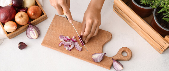 Woman cutting red onion on wooden board