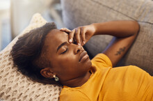 Tired, Bored And Exhausted Female Sleeping On A Couch At Home. African Female Relaxing And Resting On A Sofa Due To Headache Or Migraine In Her House. Lady Lying Down And Dreaming While Taking A Nap