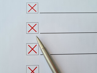 Ballpoint pen crosses off checklist items with a red X on white paper