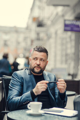 A handsome man sits and writes, thinks.Focused young businessman sitting at desk outside, and writing in notepad, handsome millennial male entrepreneur taking notes.