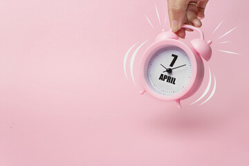 April 7th. Day 7 of month, Calendar date. The morning alarm clock jumping up from the bell with calendar date on a pink background.  Spring month, day of the year concept.