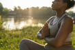 © gpointstudio - African American woman practicing breathing exercise at the park