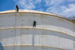 © chitsanupong - Male two worker down height tank roof rope access safety inspection thickness weld of storage tank gas