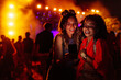 © bernardbodo - Two female friends using cellphone at music festival