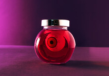 Funny Eye Ball In A Glass Jar, Creative Halloween Layout Against Purple Background. Preserved Food, Jam Or Jelly Idea. Horror Elements. 