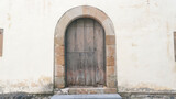 Fototapeta Desenie - Puerta de madera en forma de arco en fachada antigua de piedra