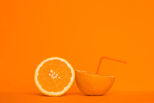 Minimalistic idea with a juicy orange cut into two halves. Summer refreshing drink made of citrus fruits. Vitamins, the concept of fresh healthy food.