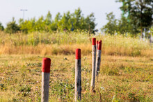 Three Wooden Posts With A Red Top In A Row On A Field With Depth Blur
