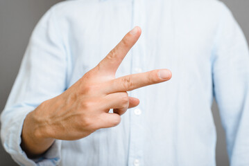 Symbol of peace, sign of victory. Close-up of an unrecognizable man in blue shirt showing two fingers