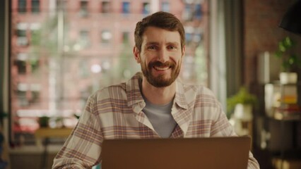 Fototapete - Portrait of a Happy Handsome Caucasian Man Working on Laptop Computer in Stylish Cozy Living Room. Freelancer Working From Home. Man Posing for Camera, Charmingly Smiling.