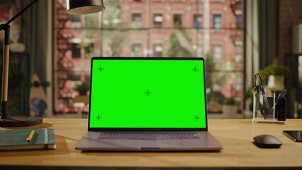 Fototapete - Laptop Computer Display with Mock Up Green Screen Standing on Wooden Table with a Notebook and Smartphone in Living Room. Chroma Key Monitor at Home or Creative Loft Office.