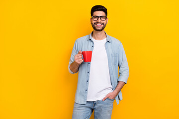 Wall Mural - Photo of friendly latin young man relaxing have free time coffee cup wear trendy denim look eyewear isolated on yellow color background