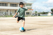 学校でサッカーをしている小学生の男の子