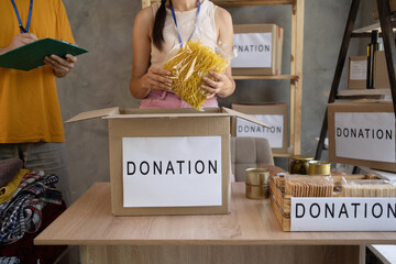 woman volunteer with food in box at distribution or refugee assistance center. charity, donation and volunteering