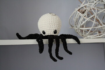 Wall Mural - knitted black and white toy octopus in the interior of pastel colors on the shelf