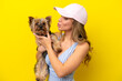 © luismolinero - Young caucasian woman holding a puppy isolated on yellow background