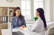© Studio Romantic - Joyful young woman talks to female doctor who supports and comforts her during reception. Friendly doctor and smiling female patient holding hands sitting at table in medical office