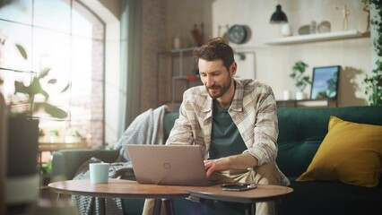Aufkleber - Happy Man Working from Home on Laptop Computer in Sunny Cozy Apartment, Relaxing on a Sofa. Successful Creative Male Entrepreneur Leans Back in Joy After Finishing Remote e Commerce Work. Zoom out