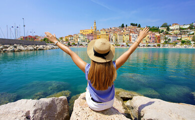 Wall Mural - Traveling in France. Panoramic view of traveler girl with arms raised enjoying view of Menton village, French Riviera.