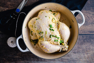 Cuban Mojo Chicken Ingredients on a Wood Background: Raw whole chicken, citrus fruit, cilantro, and other ingredients for marinated roast chicken