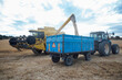 © ADDICTIVE STOCK - Combine harvester unloading grains in countryside