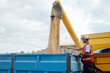 © ADDICTIVE STOCK - Worker standing near combine harvester unloading grains