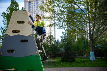 Wall Mural - Teenager boy climbing at kid playground outdoor. The climber tra