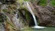 Klares Wasser sprudelt über einen schönen Wasserfall in ein Becken. Die Felsen sind vom Wasser geformt.
