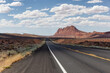 Scenic Road in the Dry Desert with Red Rocky Mountains in Background.