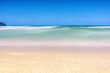 Langzeitbelichtung eines Sandstrandes mit türkisblauem Meer vor blauem Himmel