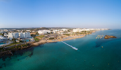 Wall Mural - Aerial bird's eye view of Fig tree bay in Protaras, Paralimni, Famagusta, Cyprus. Tourist attraction golden sandy beach with boats, sunbeds, sea restaurants, water sports on summer holidays from above