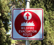 Red wildfire evacuation route sign with ahead arrow that point in the correct direction of voluntary or mandatory egress during fire emergency