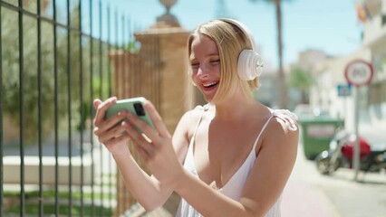 Poster - Young blonde woman smiling confident watching video on smartphone at street