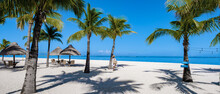 Le Morne Beach Mauritius Tropical Beach With Palm Trees And White Sand Blue Ocean And Beach Beds With Umbrellas, Sun Chairs, And Parasols Under A Palm Tree At A Tropical Beach. Mauritius Le Morne