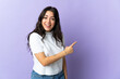 © luismolinero - Young caucasian woman isolated on purple background surprised and pointing side