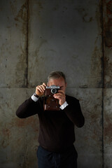 Wall Mural - Front view of elderly man take photo on old camera