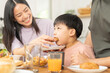 Happy refreshment family breakfast in morning, asian young parent father, mother and little cute boy, child having meal in kitchen eating together at home. Cheerful, enjoy cooking people.