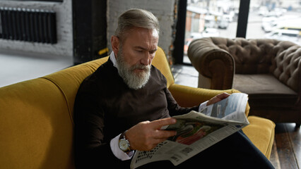 Wall Mural - Grey hair man reading newspaper on sofa in flat