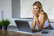 © dianagrytsku - Happy young woman using laptop in kitchen