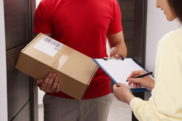 Wall Mural - Woman signing for delivered parcel at home, closeup