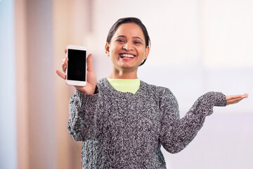 Wall Mural - Cheerful young adult indian woman showing modern smartphone