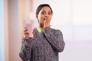 Wall Mural - Portrait of young women showing blank screen of mobile phone and covering her mouth