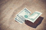 Fototapeta  - Money dollars half covered with sand lie on beach close-up. Dollar bills partially buried in sand. Three hundred dollars buried in sand on sea ocean beach Concept finance money holiday relax vacation