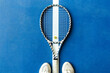 The tennis racket lies on a blue tennis surface, the toes of the sneakers are directed towards the racket.